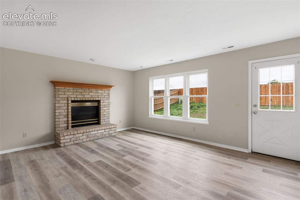 Image 16 of 38: Living area featuring a brick fireplace with a wood mantle, wood-finish flo