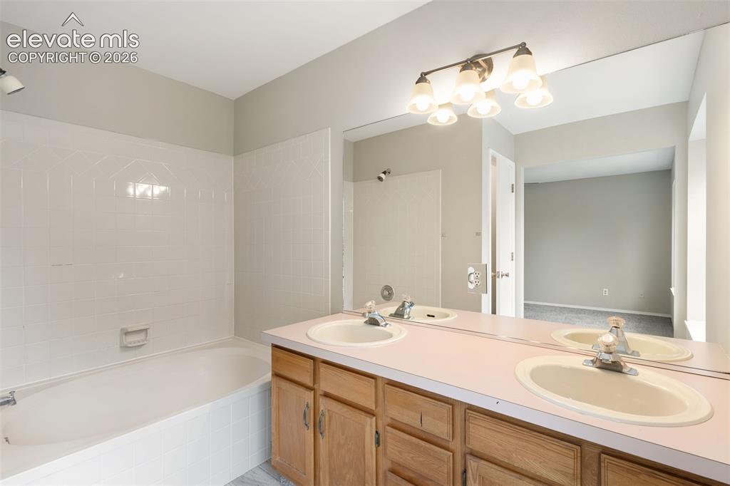 Image 25 of 38: Bathroom vanity featuring dual sinks with individual faucets, wood cabinetr