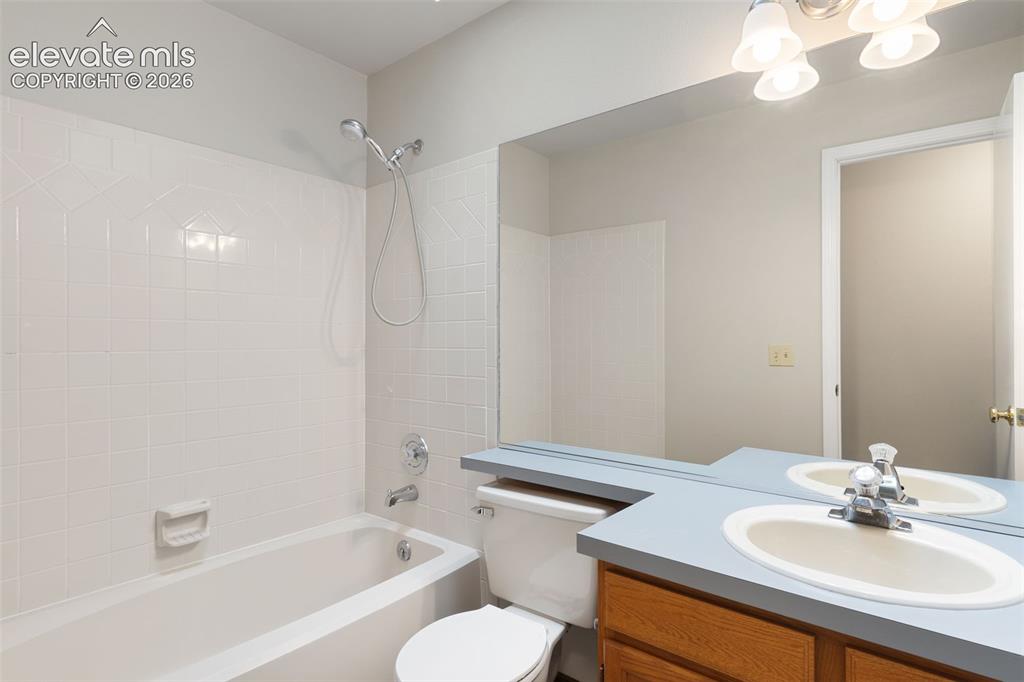 Image 34 of 38: Full bathroom featuring a white porcelain tub with shower, white tiled surr