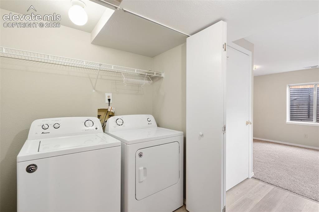 Image 35 of 38: Dedicated laundry area featuring a white washing machine and dryer, overhea