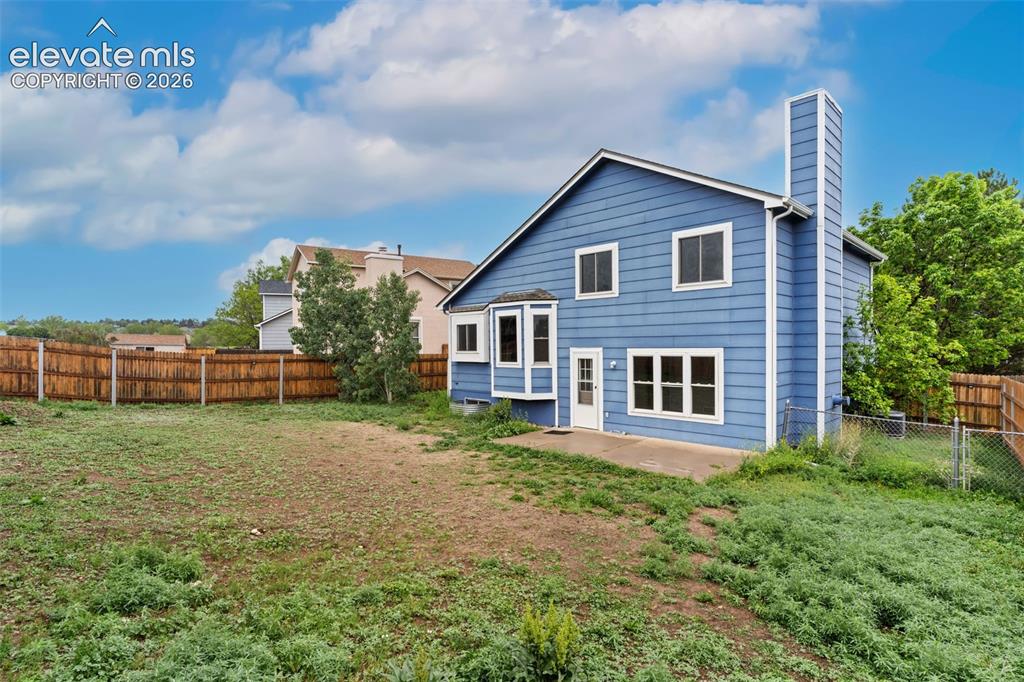 Image 37 of 38: Spacious backyard featuring a wood fence, concrete patio, bay window, and a
