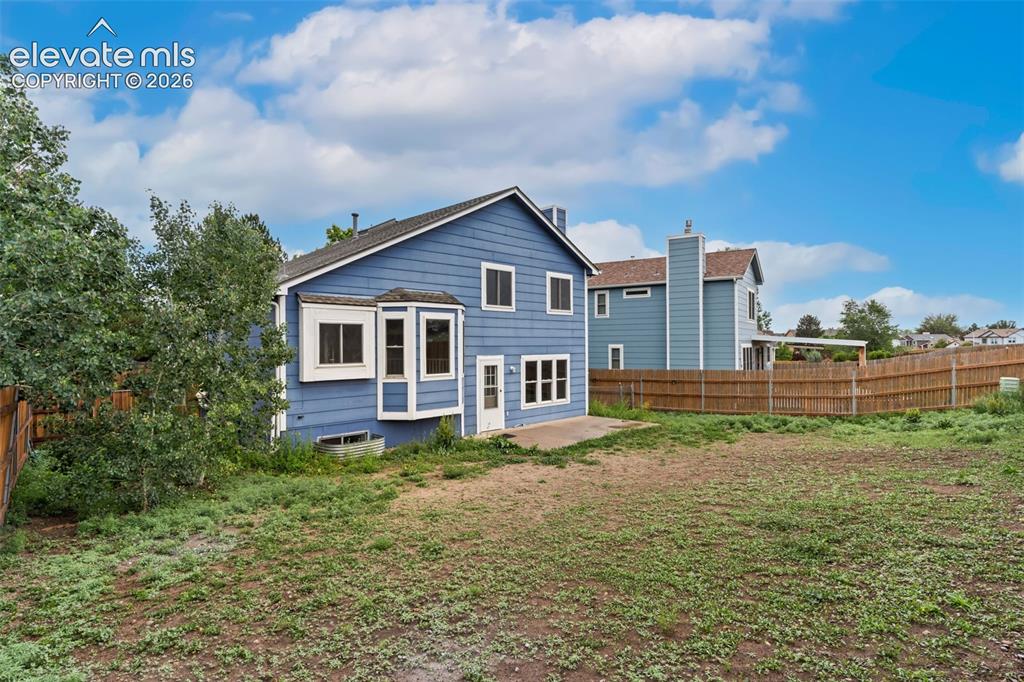 Image 38 of 38: Spacious backyard featuring a sloped grade, mature trees, and a full privac