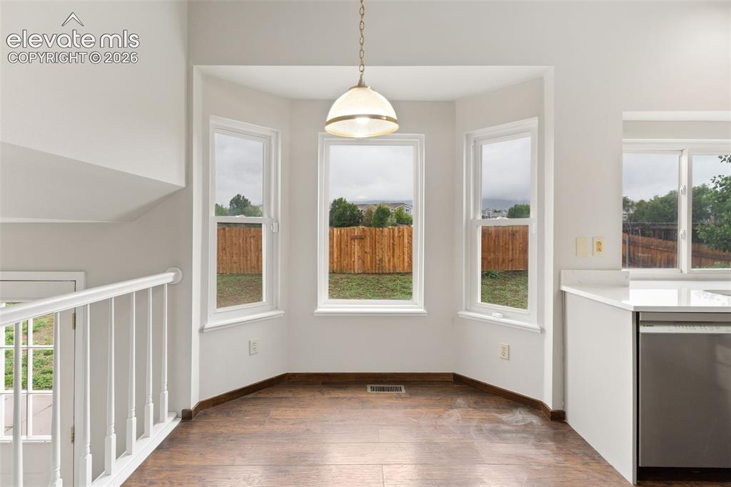 Image 8 of 38: Dining area featuring a bay window, wood-finish flooring, and an overhead l