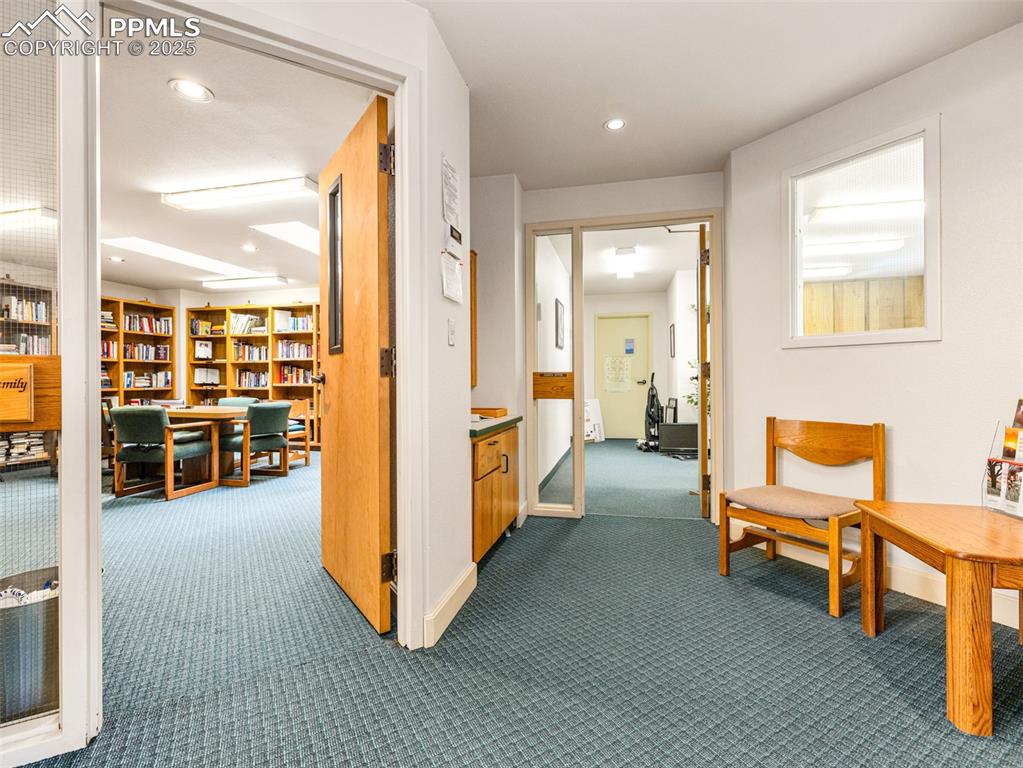 Image 15 of 49: Hall with dark colored carpet, recessed lighting, and a desk