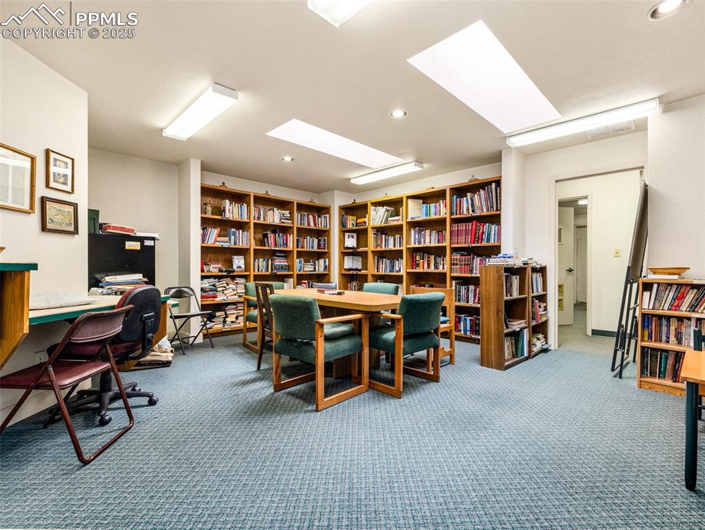 Image 16 of 49: Carpeted office featuring bookshelves, a skylight, and recessed lighting