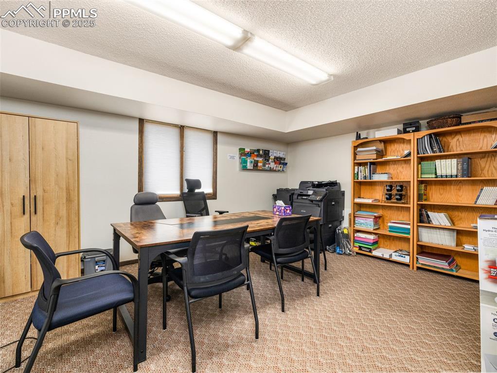 Image 21 of 49: Office area with a textured ceiling and light colored carpet