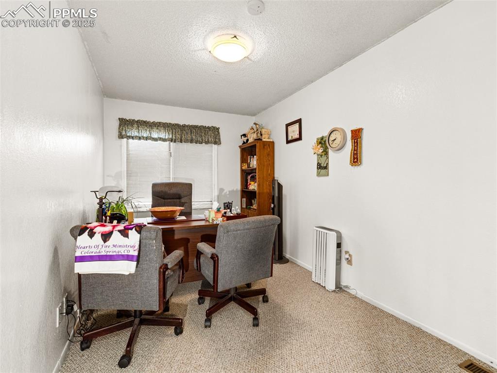 Image 29 of 49: Carpeted home office with a textured ceiling and baseboards