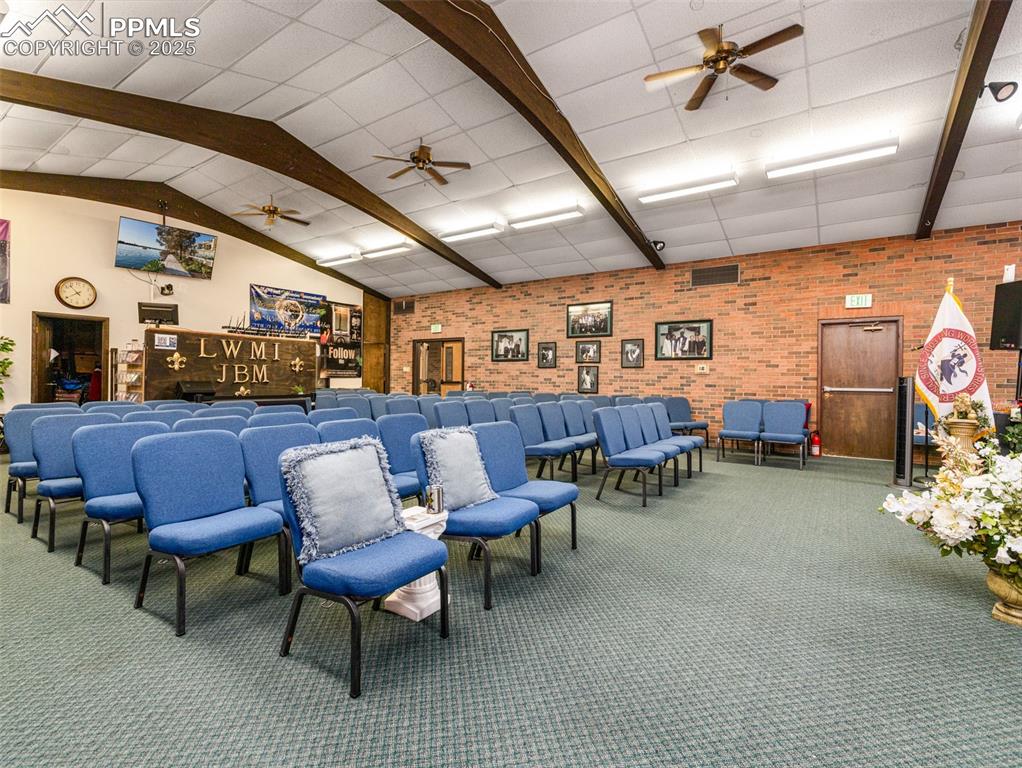 Image 32 of 49: Miscellaneous room with ceiling fan, brick wall, carpet floors, and beam ce
