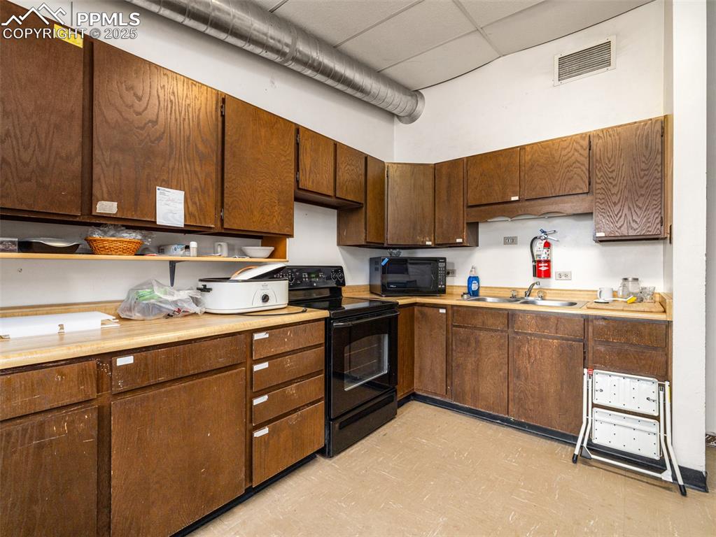 Image 36 of 49: Kitchen featuring light floors, light countertops, black appliances, and a 