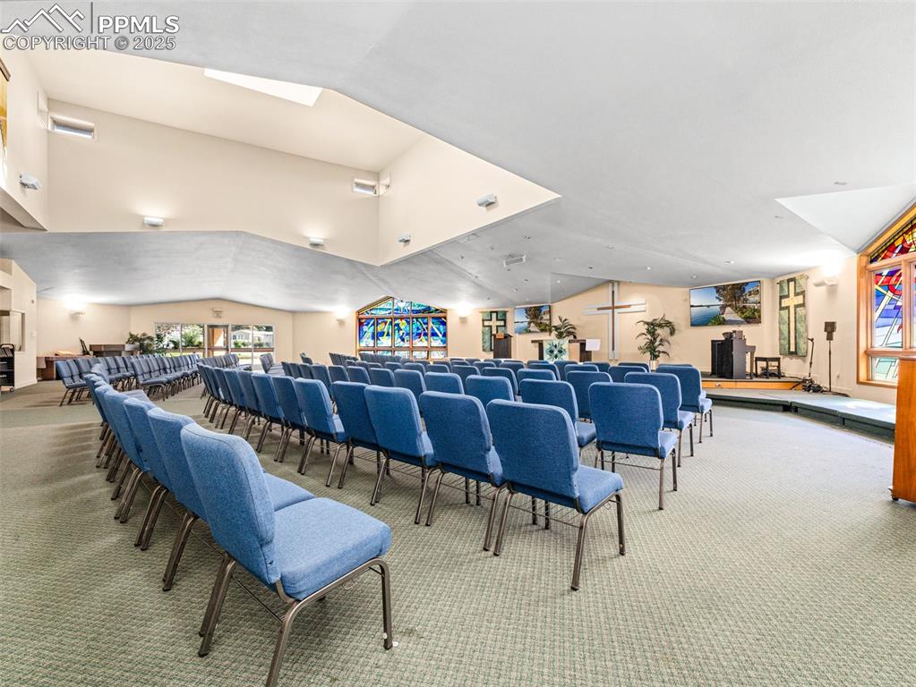 Image 44 of 49: Carpeted home theater with vaulted ceiling and a skylight