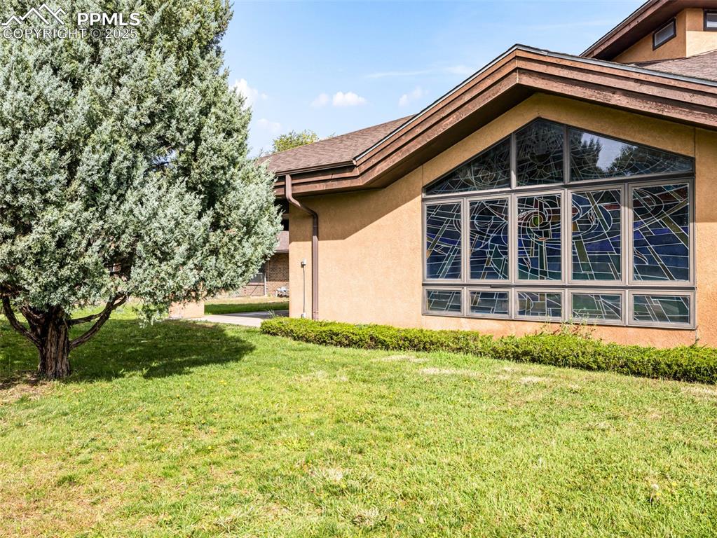 Image 6 of 49: View of side of home with stucco siding and a yard