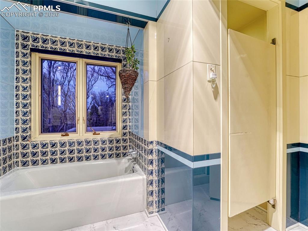 Image 28 of 50: Primary Suite sitting room w/Kiva fireplace & Vigas ceiling.