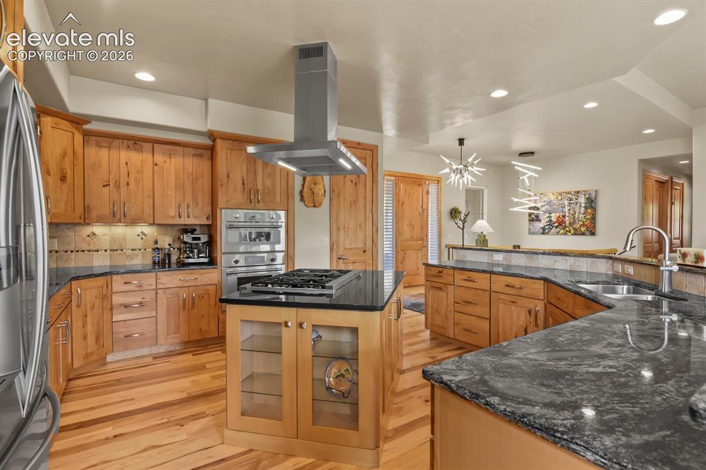 Image 11 of 48: Gourmet kitchen featuring wood-finish cabinetry, dark stone countertops, st