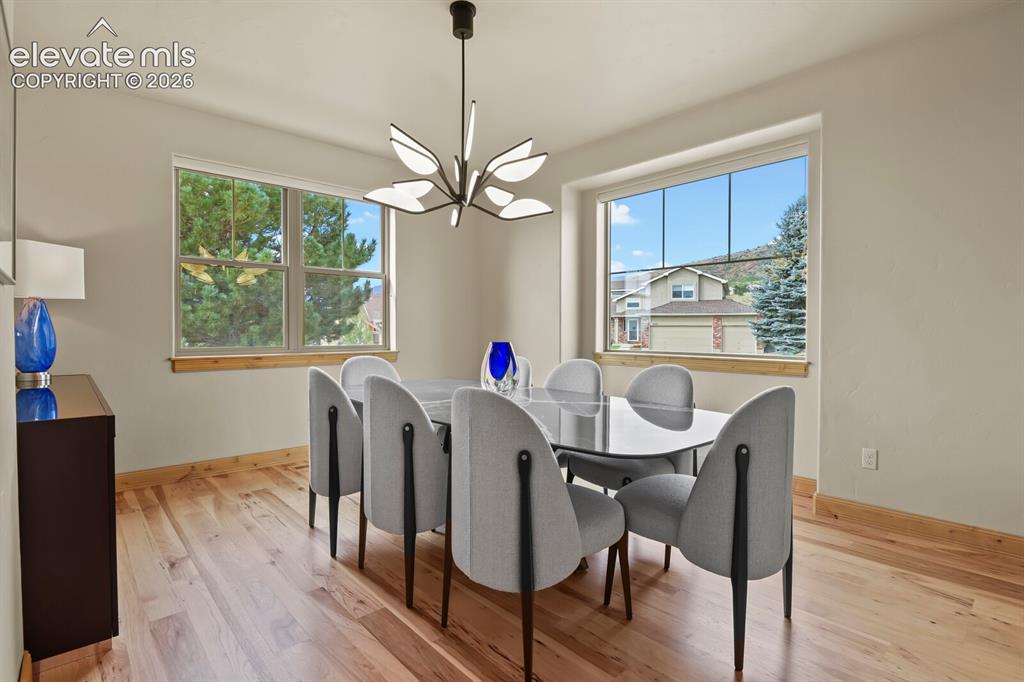 Image 16 of 48: Formal dining room with hardwood flooring, contemporary chandelier, two lar