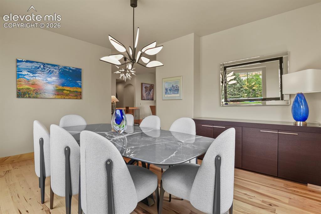 Image 17 of 48: Sleek dining area featuring wood-finish flooring, a modern chandelier, and 
