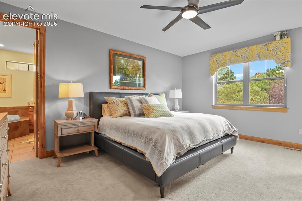 Image 18 of 48: Plush carpeting, ceiling fan with integrated lighting, and a large window w