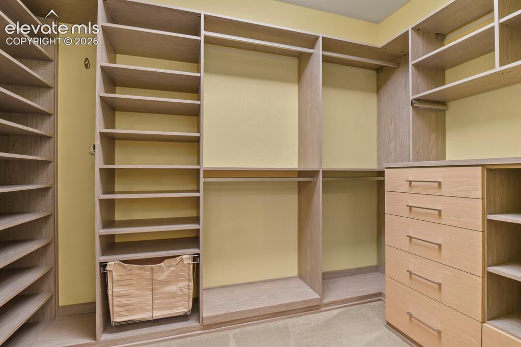 Image 22 of 48: Primary bedroom custom closet system featuring extensive shelving, multiple