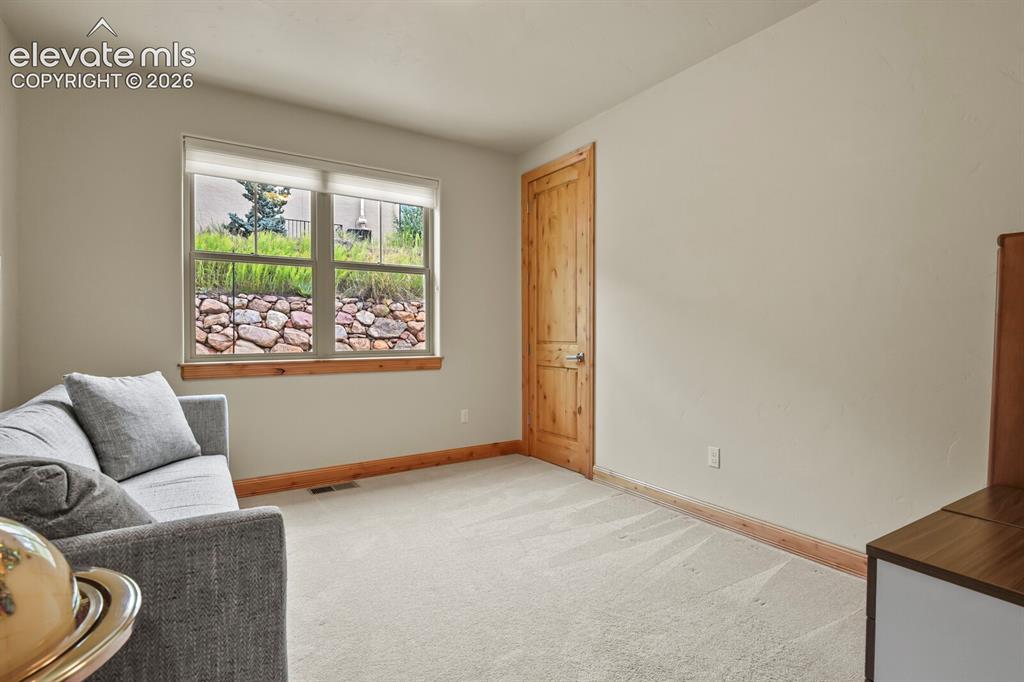 Image 23 of 48: Main level bedroom with a large window, natural wood trim, and a wood-panel