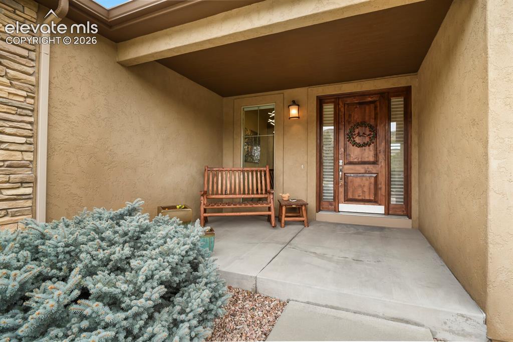 Image 3 of 48: Covered entry with a solid wood door, sidelight windows, and an exterior wa