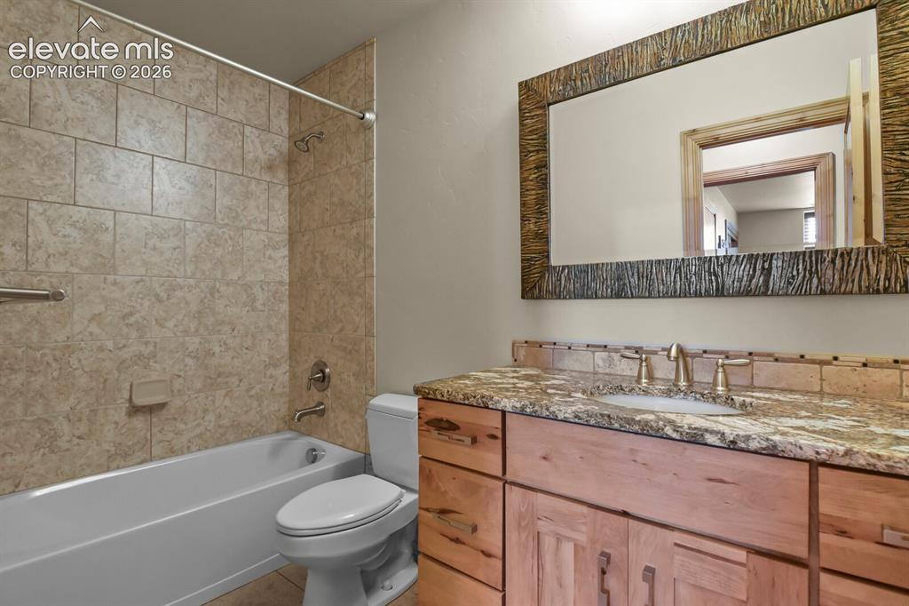 Image 30 of 48: Basement bathroom featuring a tiled shower surround, built-in bathtub, wood