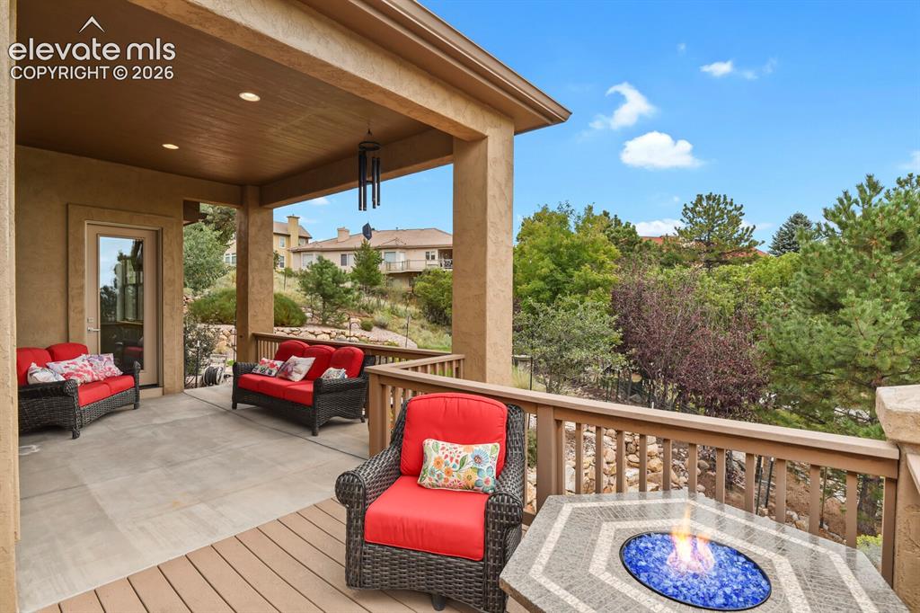 Image 35 of 48: Covered outdoor patio with a planked deck section, concrete patio, wood rai