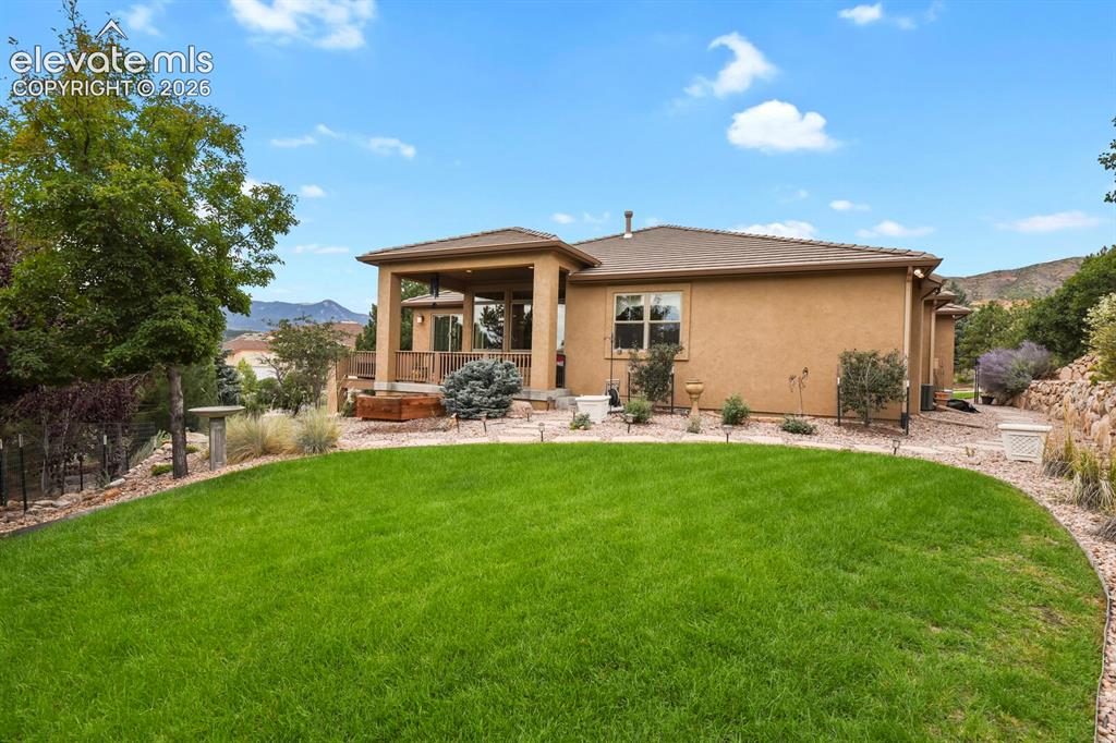 Image 37 of 48: Backyard featuring a manicured lawn, covered patio, stucco exterior, and sl