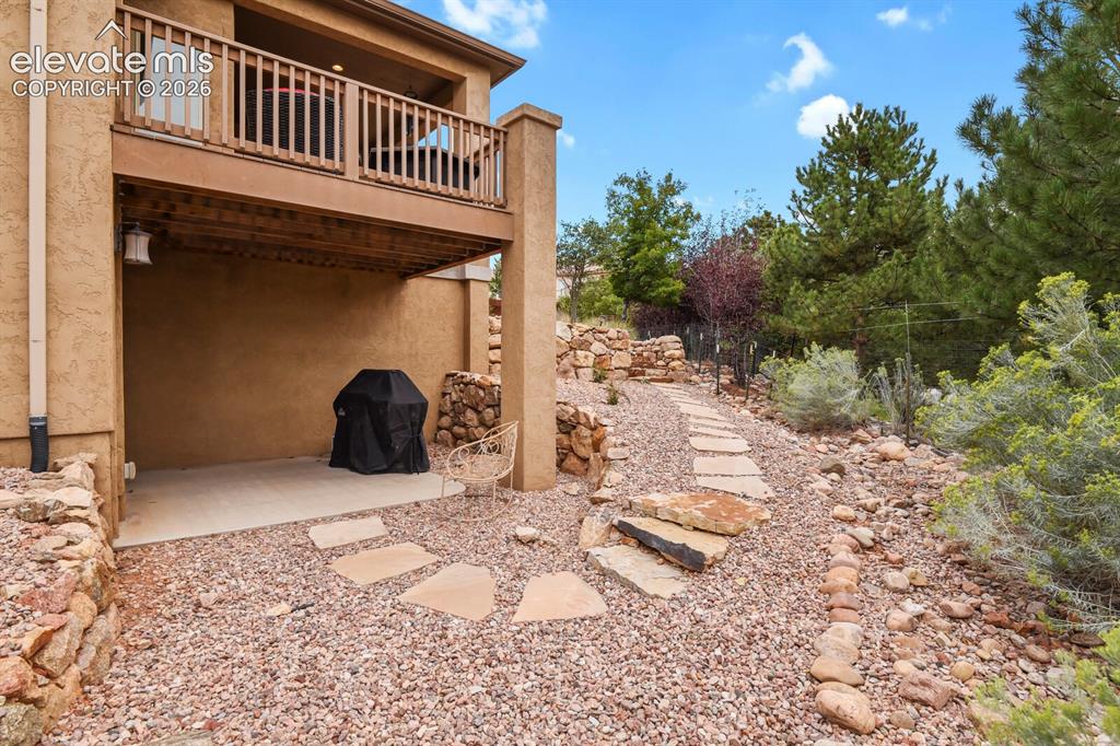 Image 39 of 48: Upper-level balcony with wood railing, lower-level concrete patio, and a na