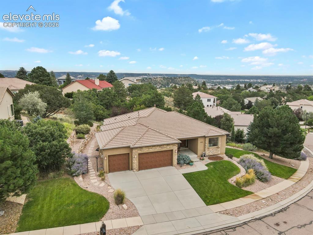 Image 40 of 48: Tile roof, three-car garage with wood-finish doors, concrete driveway, land
