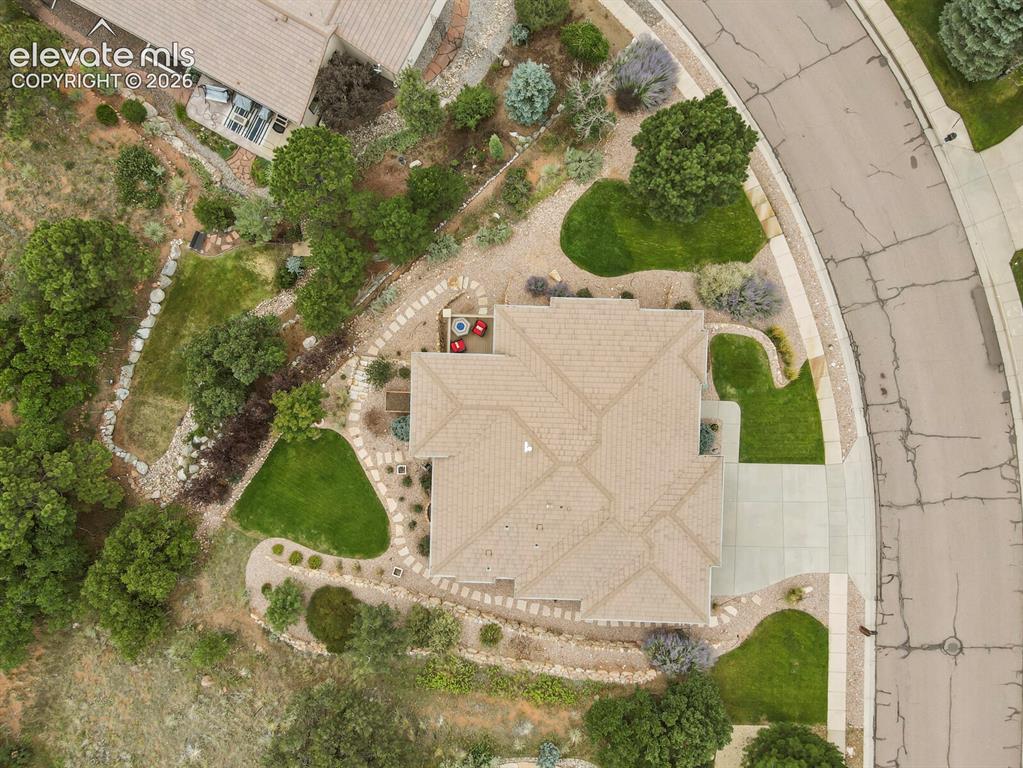 Image 46 of 48: Paved driveway, concrete walkways, tiled roof, landscaped grounds, and ston