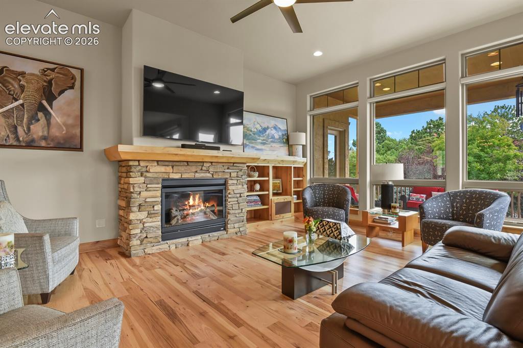 Image 5 of 48: Stone-clad fireplace with wood mantel, custom hardwood flooring, built-in s