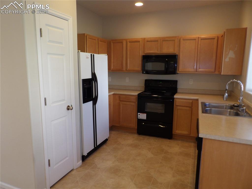 Image 12 of 20: Kitchen featuring black appliances, light countertops, recessed lighting, a