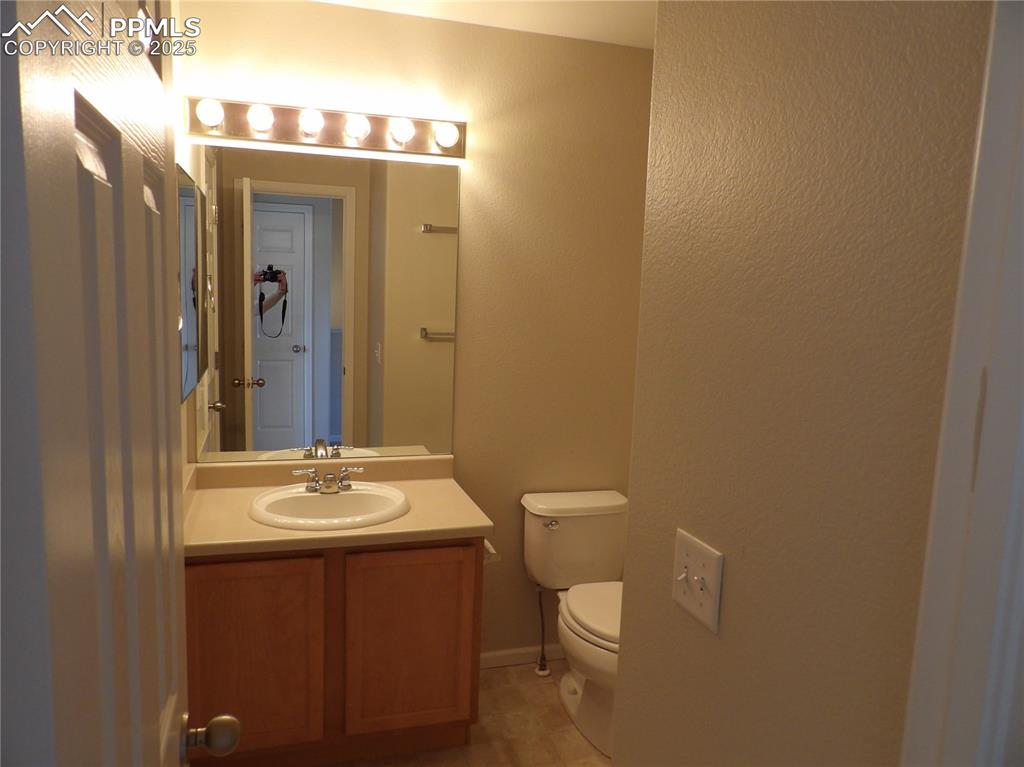 Image 18 of 20: Half bath featuring vanity, light tile patterned floors, and a textured wal