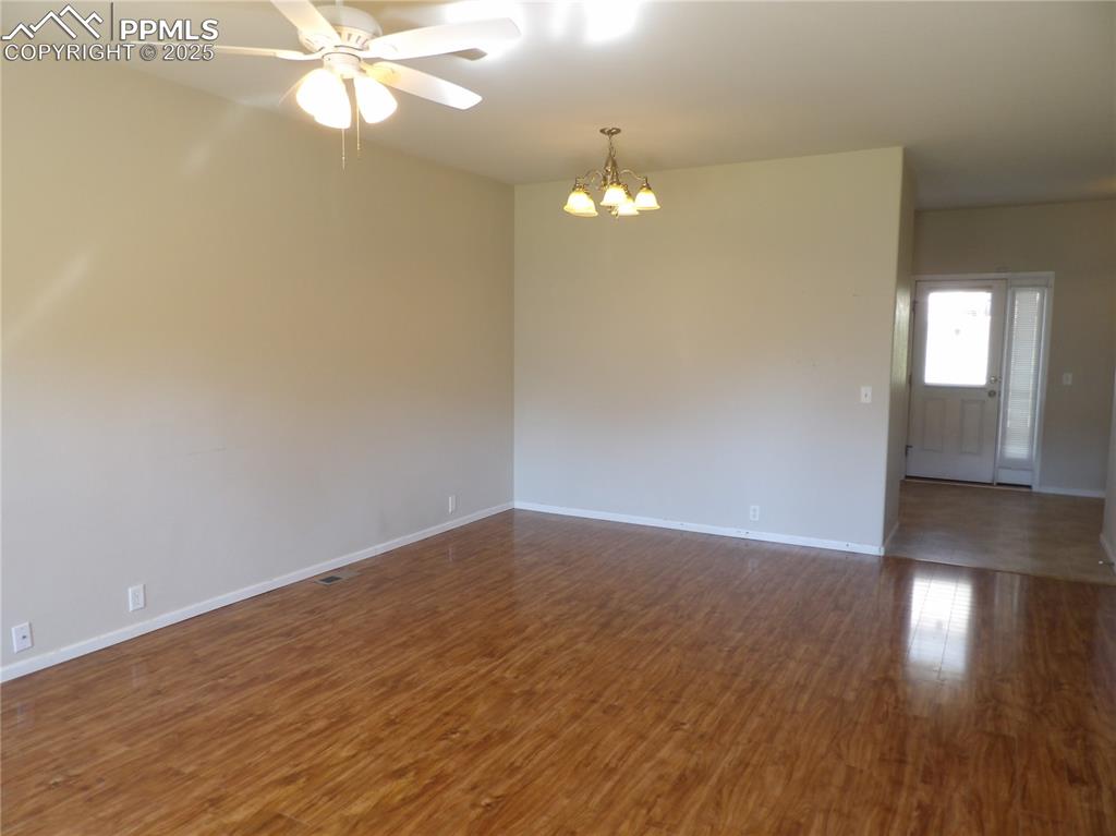 Image 4 of 20: Unfurnished room featuring a chandelier, ceiling fan, and dark wood-style f