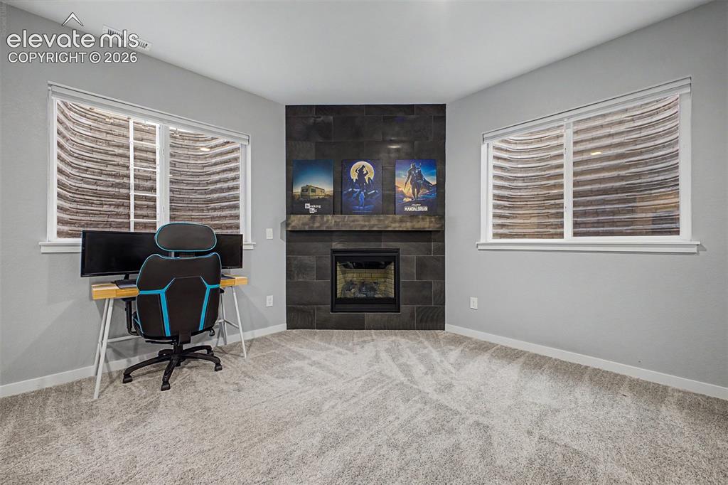 Image 41 of 50: Corner fireplace with dark stone surround, wood-finish mantel, and integrat