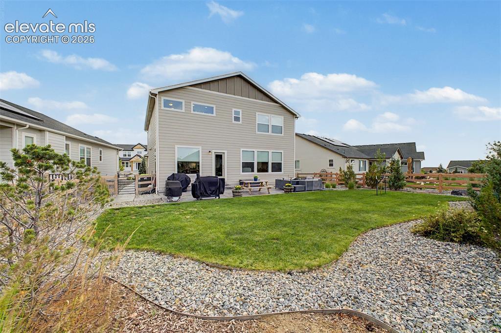 Image 45 of 50: Expansive backyard with a manicured lawn, a gravel border, and a concrete p