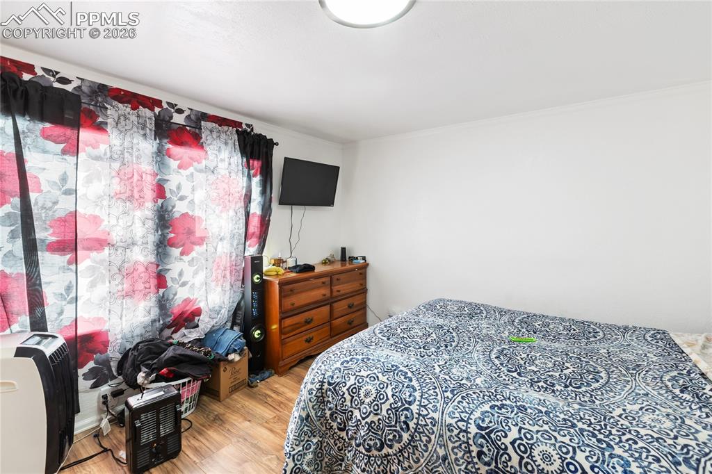 Image 20 of 37: The bedroom featuring wood finished floors and ornamental molding