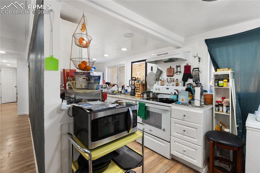 Image 8 of 37: The kitchen with light wood-style floors, white electric range, stainless s