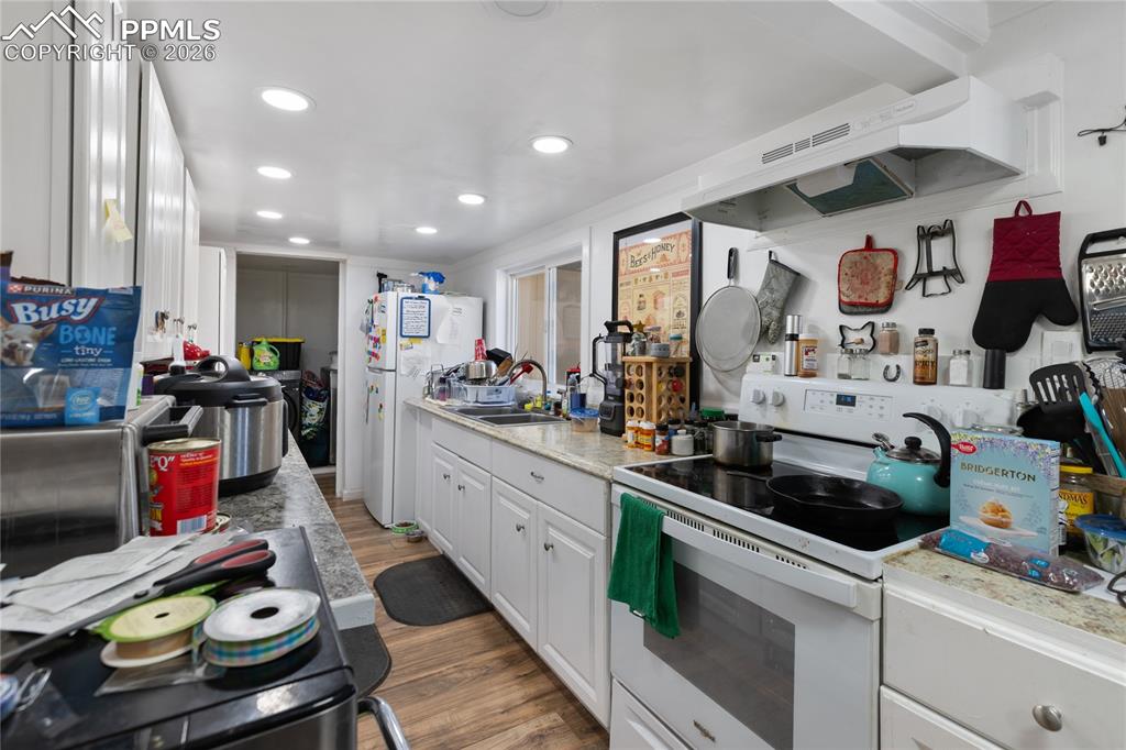 Image 9 of 37: Kitchen with white appliances, white cabinets, light countertops, light woo