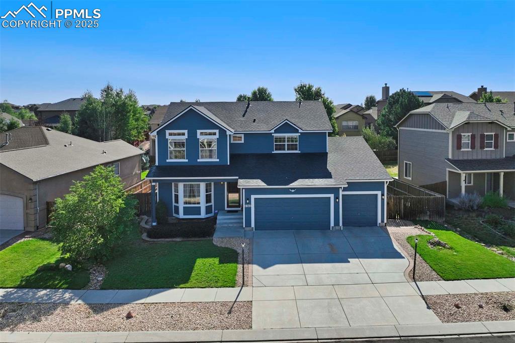 Caption: Traditional-style house featuring a residential view, concrete driveway, an attached garage, and a g
