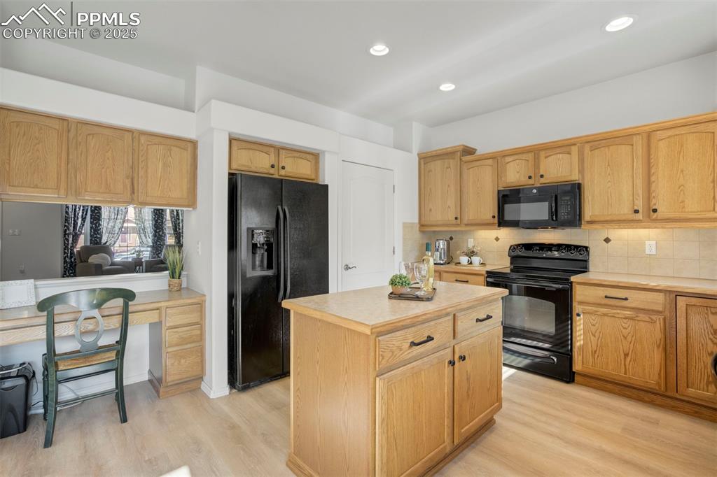 Image 12 of 50: Kitchen featuring black appliances, tasteful backsplash, light countertops,