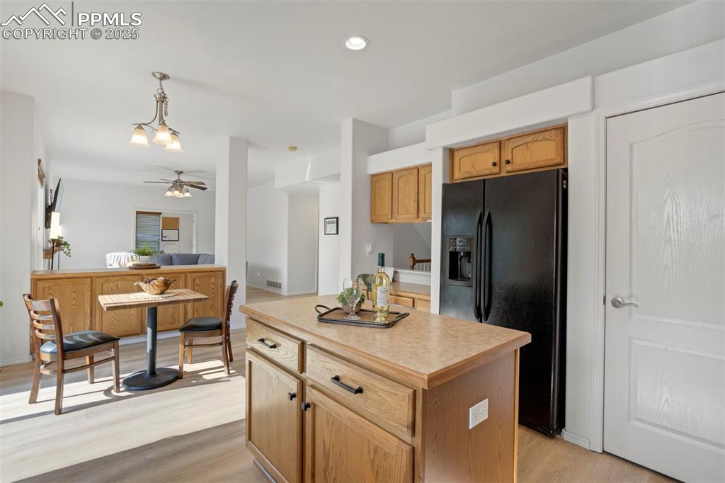 Image 13 of 50: Kitchen with black refrigerator with ice dispenser, light wood-style floori