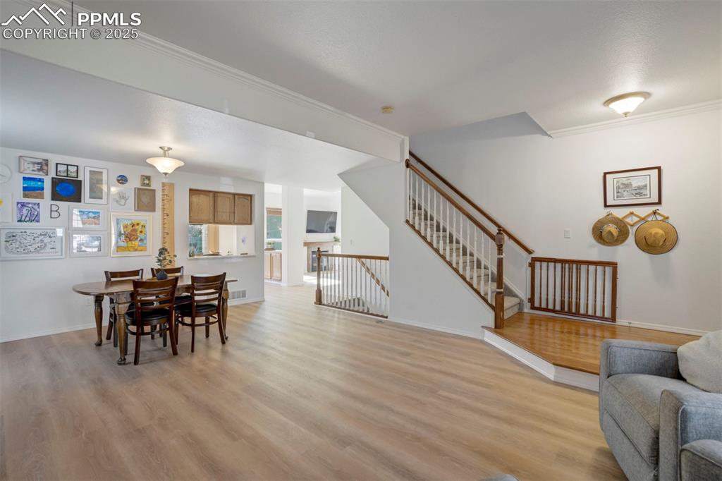Image 15 of 50: Dining room with crown molding, light wood-type flooring, and stairway