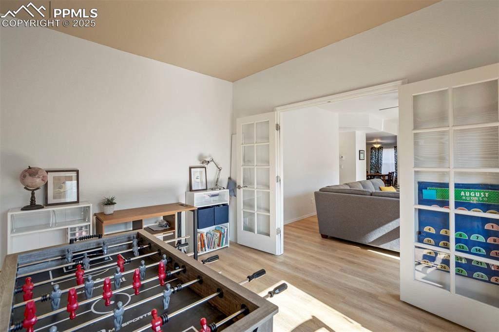 Image 18 of 50: Recreation room with light wood-style floors and french doors