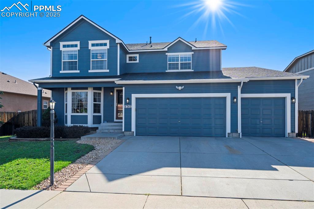 Image 2 of 50: Traditional home featuring concrete driveway, covered porch, a garage, and