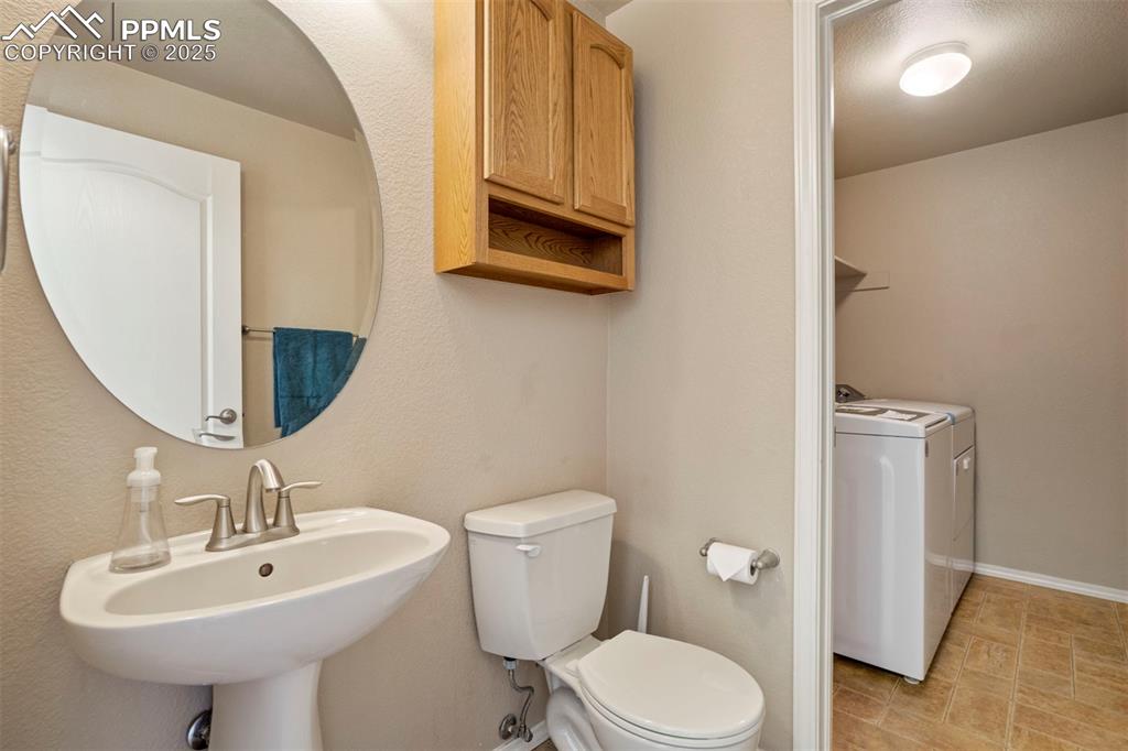 Image 20 of 50: Half bath featuring toilet and washer and dryer