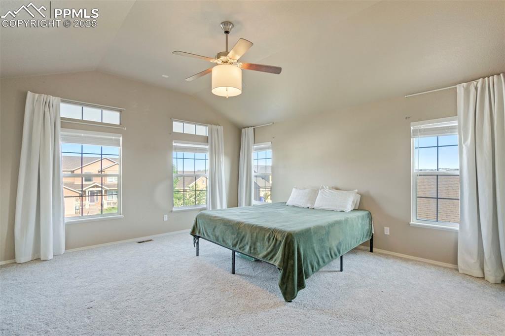 Image 24 of 50: Carpeted bedroom featuring multiple windows, vaulted ceiling, and ceiling f