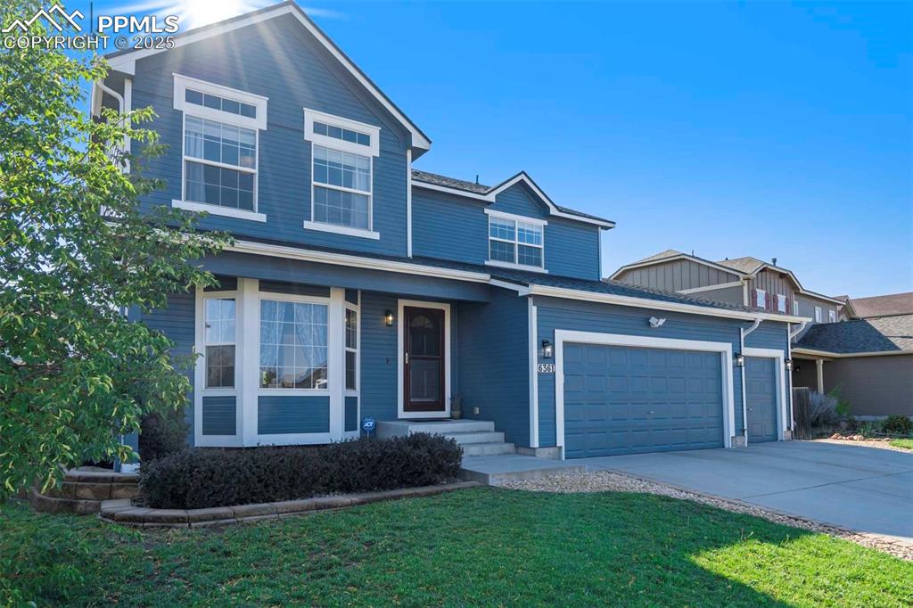 Image 3 of 50: Traditional-style house featuring driveway, a garage, and a front yard