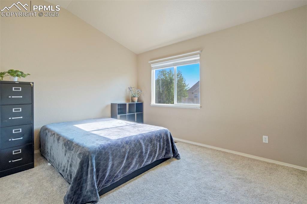 Image 32 of 50: Bedroom featuring lofted ceiling and carpet floors