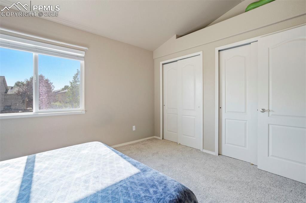 Image 33 of 50: Carpeted bedroom with vaulted ceiling and baseboards
