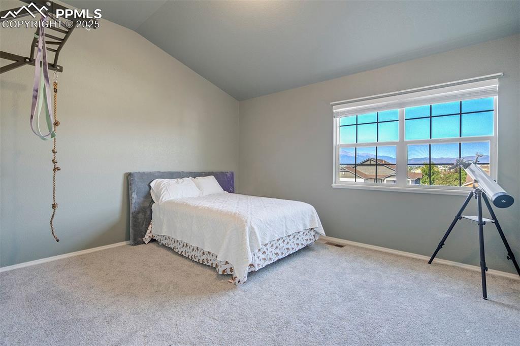 Image 36 of 50: Bedroom featuring vaulted ceiling and carpet flooring